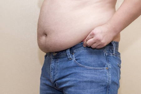 Man wearing blue jeans, fat belly closeup, the problem of overweightの写真素材