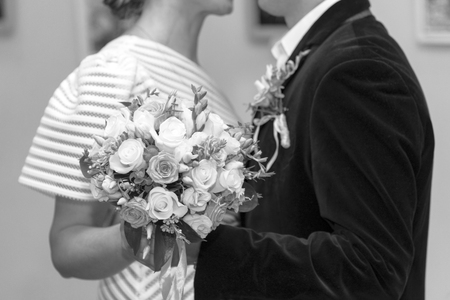 Bride and groom are holding a bouquet of roses at a wedding, close-up, black and white photoの写真素材