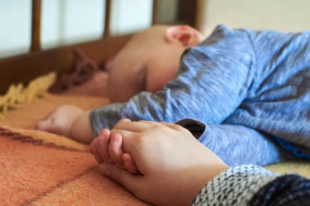 The baby holds her mom's hand while sleepingの写真素材