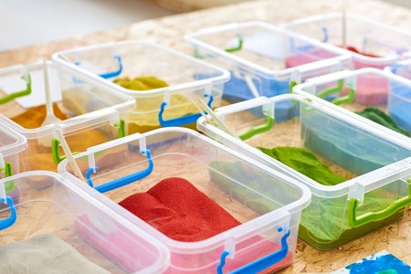 Multi-colored sand for drawing in plastic containers, close-up
