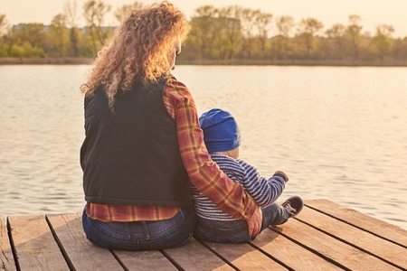Mom hugs her little son on the pier on the river, toned photoの写真素材