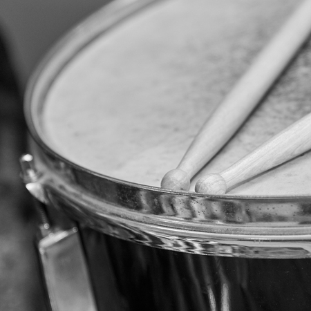 Two wooden drumsticks lie on the drum, black and white photoの写真素材