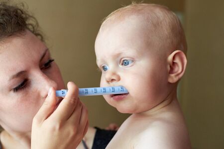 Mom gives her little child medicine through a syringeの写真素材