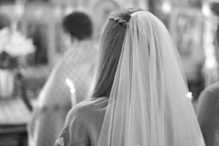 Bride with a candle in the church, the wedding ceremony in the Christian church. Rear view. Black...