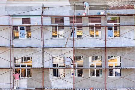 Few workers paint and plaster the facade of the houseの写真素材