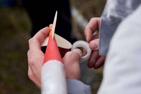 The guy holds in his hands a model of a miniature rocket and prepares it for flight.