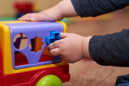 The child puts the figures in a sorter colorful car, educational toys for children.