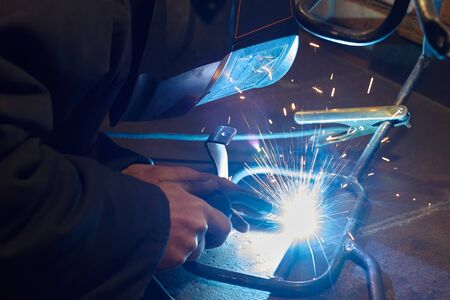 A man in a protective mask carries out welding work in the garage.