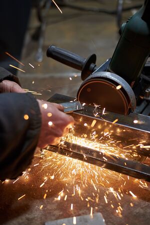 Hands of a man who cuts a metal part on a machine tool in a garage, close-up.