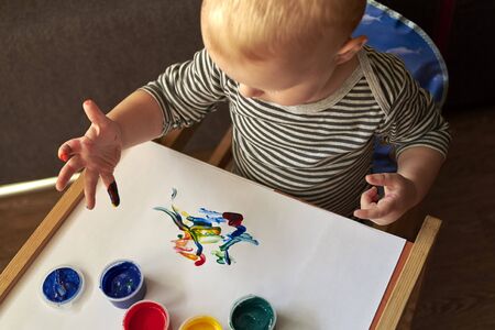 A small boy draws with bright colors with his fingers, the early development of the child.の写真素材