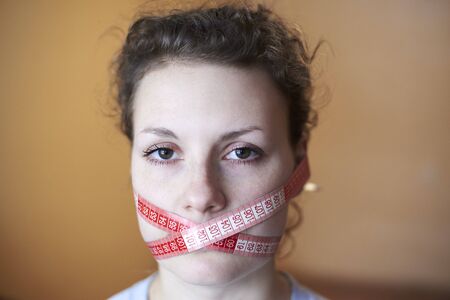 Sad woman with wrapped face meter around face, topic of losing excess weight, diet and stress.の写真素材