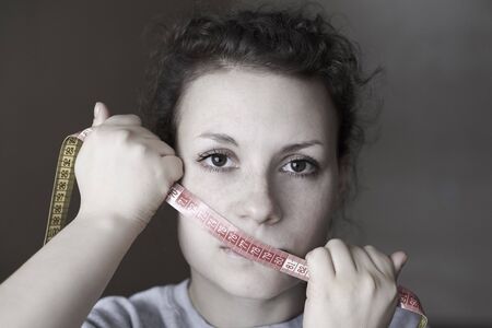 Sad woman with meter on the mouth, topic of losing excess weight, diet and stress.の写真素材