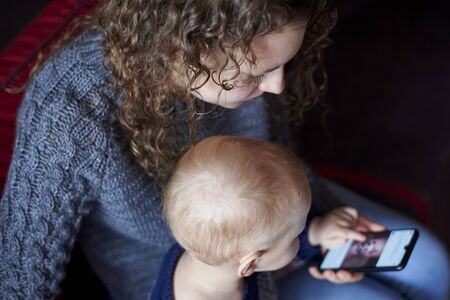 Mom shows her little son how to use a mobile phone, the early development of the child.