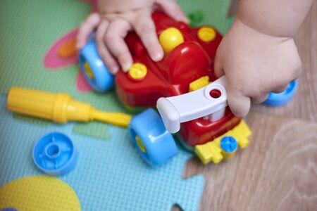 The boy plays with a car that can be disassembled, educational toys for children.