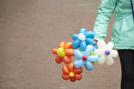 Balloons in the form of a flower in the hands of a girl walking down the city street.