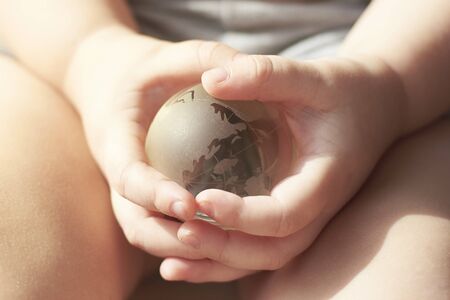 Glass transparent globe, planet Earth, in the hands of a child.