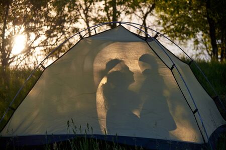 Silhouette of mom and baby in a camping tent.の写真素材