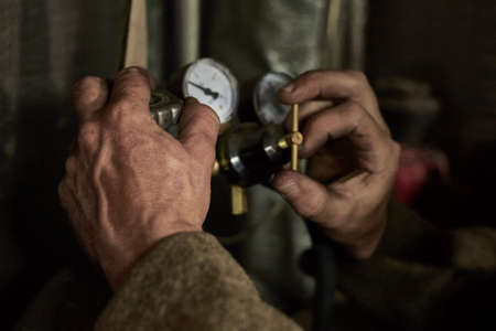 Hands of a man who works with a pressure gauge in the garage, close-up.