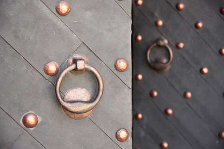 Fragment of old dark metal doors with a doorknob.