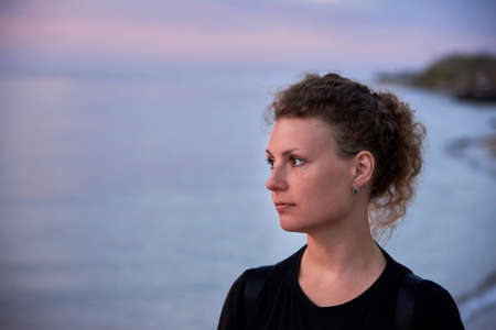 Portrait of a pretty beautiful woman against the background of the sea at sunrise.