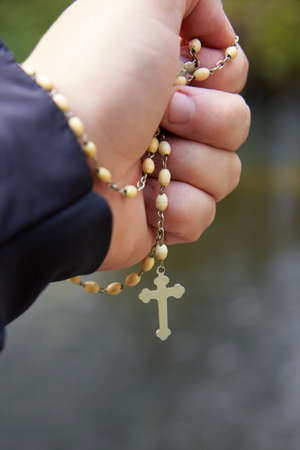 The hand of a man firmly gripping the rosary, the theme of the Christian faith.の写真素材