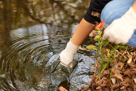 A scientist collects river water in a glass beaker for testing.