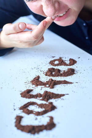 A woman rubs coffee into her gums like a drug addict, selective focus, caffeine addiction concept.の写真素材