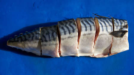 Fresh chopped mackerel laid out on a blue plastic cutting board.