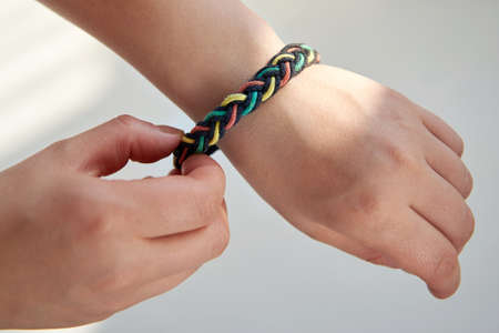 Bracelet made of fabric ropes on a woman's hand on a white background, close-up.の写真素材