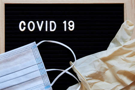 The inscription Covid 19 on a black background, medical masks and latex gloves, protection from the corona virus.の写真素材