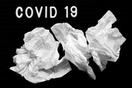 The inscription Covid 19 on a black background, paper napkins, runny nose with coronavirus.の写真素材