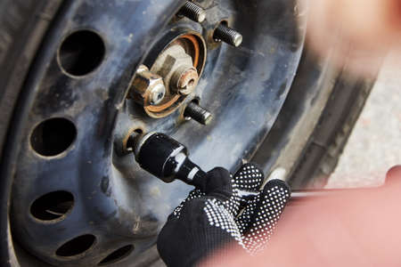 A woman removes the wheel with a key, close-up, trouble on the road.の写真素材