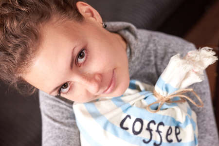 Beautiful young woman hugs a bag of coffee.