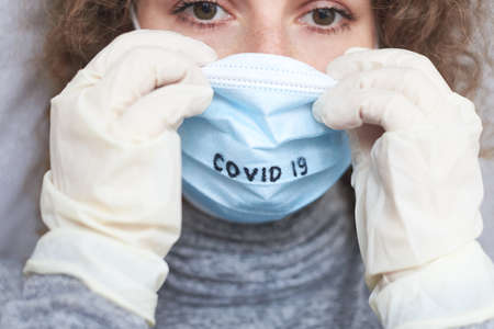 A woman wearing a medical mask with the inscription Covid 19, the theme of protection against...