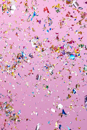 Bright colorful confetti sparkles on a pink background, the theme of a holiday and a birthday.の写真素材
