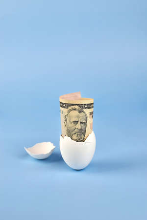 American fifty dollar bill from eggshell on blue background, earnings concept.
