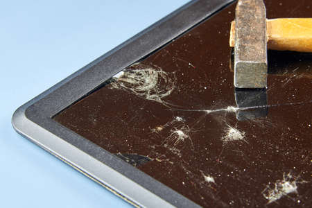 Broken laptop screen, broken glass with a hammer on it.