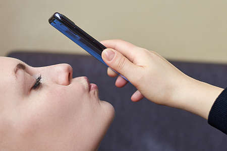 A beautiful girl kisses her smartphone during a video call, close-up.