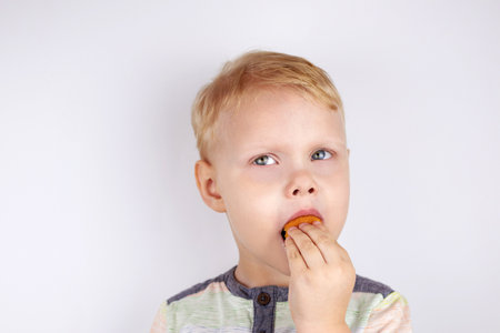 Three-year-old funny boy eats a pie on a white background.の写真素材