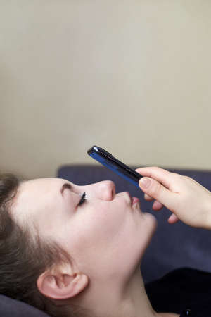 A beautiful girl kisses her smartphone during a video call, close-up.の写真素材
