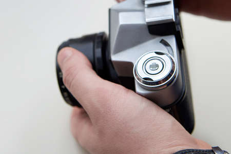 Retro photo camera in the hands of a man on a white background.
