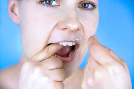 Woman brushing teeth with dental floss, close-up, dental care.の写真素材