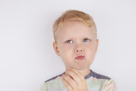 Three-year-old funny boy eats a pie on a white background.の写真素材