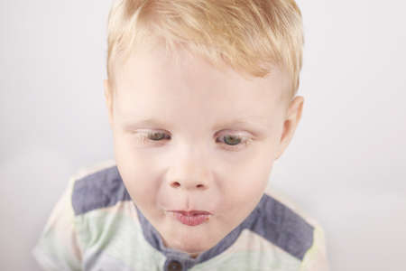Three-year-old funny boy with a mouth smeared with cake crumbs on a white background.の写真素材