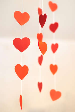 Paper red decorative hearts hang on a thread, Valentine's Day concept.の写真素材