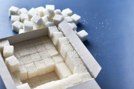 White sugar cubes in a paper box on a blue background.の写真素材