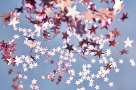 Pink glittering confetti out of focus on a blue background, creative backdrop.の写真素材