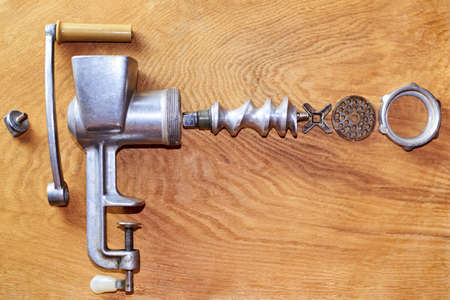 The mechanism of an old disassembled meat grinder on a wooden background.の写真素材