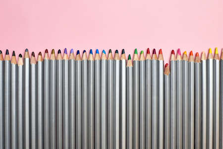 Colored pencils lined up in a row on a pink background, the theme of creativity and hobby.の写真素材