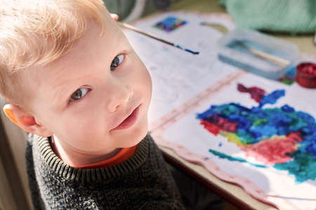 A three-year-old boy paints with gouache coloring, leisure and child development.の写真素材
